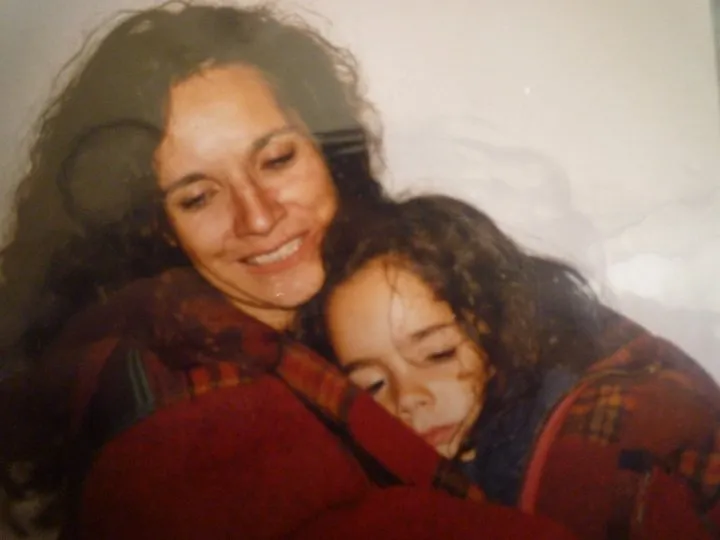 Old print: woman hugging a curly-haired child in a red blanket, warm and tender