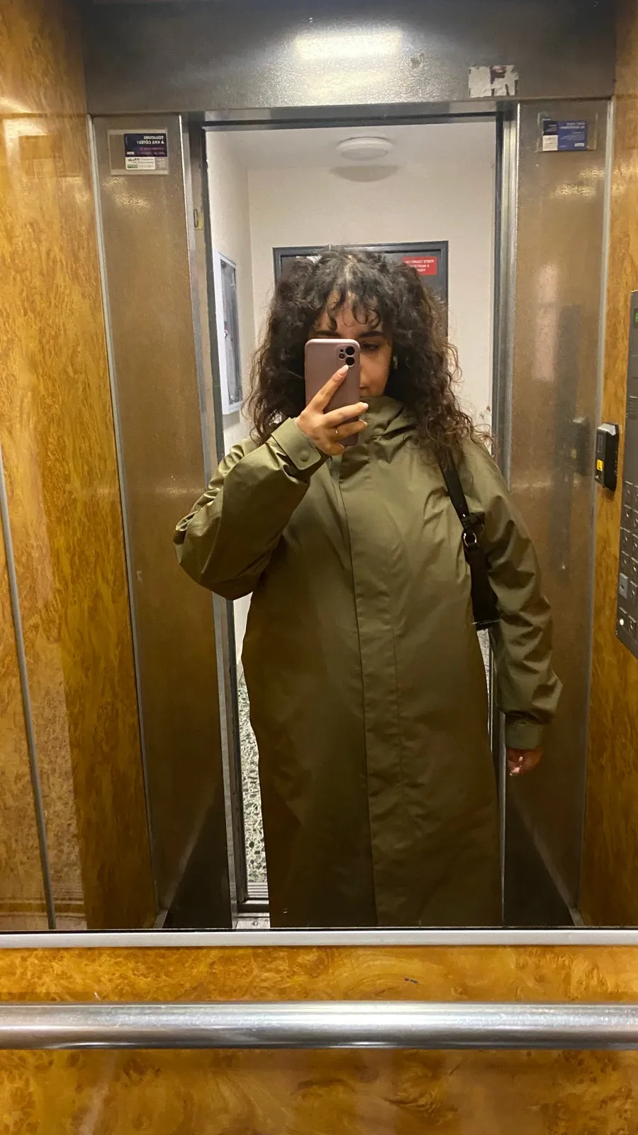Lift mirror selfie in a long khaki coat