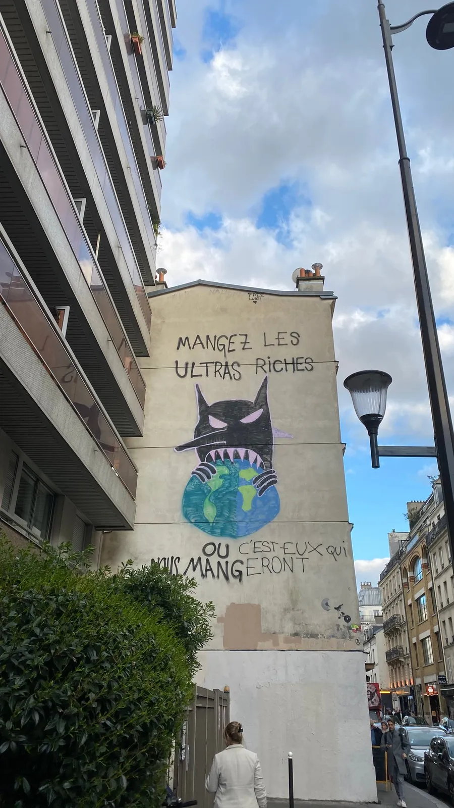 Mural 'Mangez les ultra-riches' on a gable under clouds