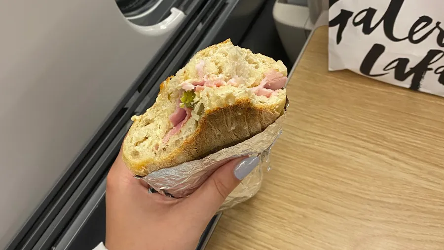 Half-eaten baguette sandwich held up in a car