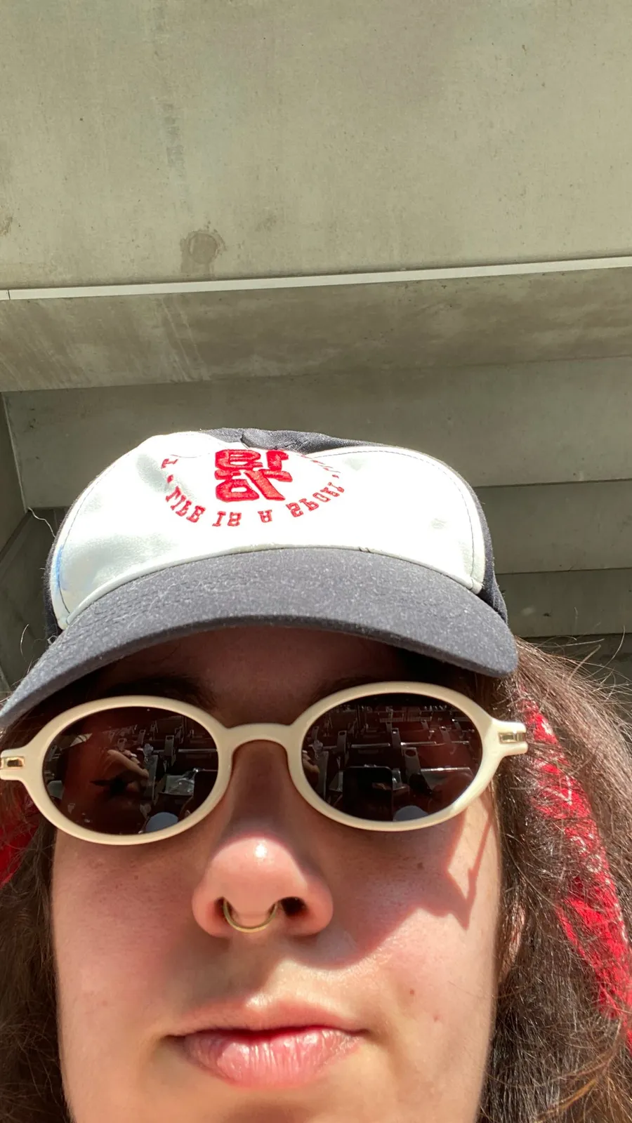 Selfie in cap and round white sunglasses, deadpan