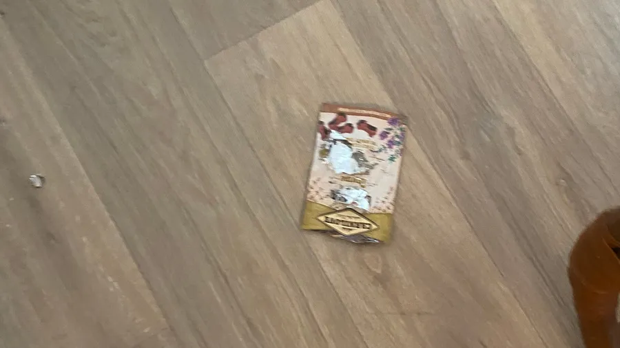 Torn candy wrapper abandoned on a wooden floor