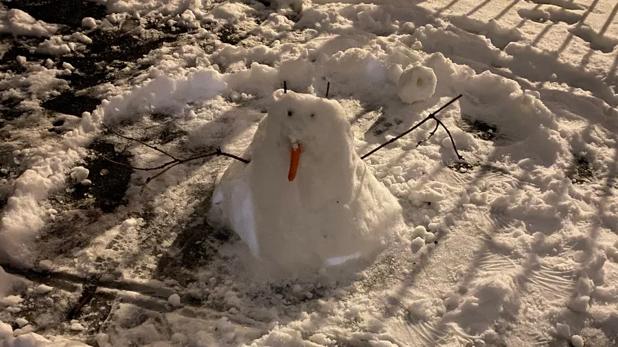 Snowman slumping in trampled snow at night