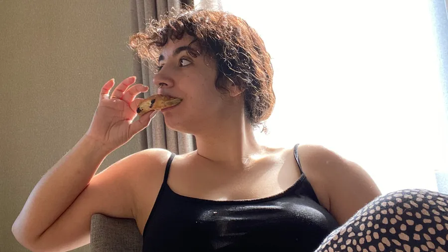 Biting a biscuit in strong window light, gaze elsewhere