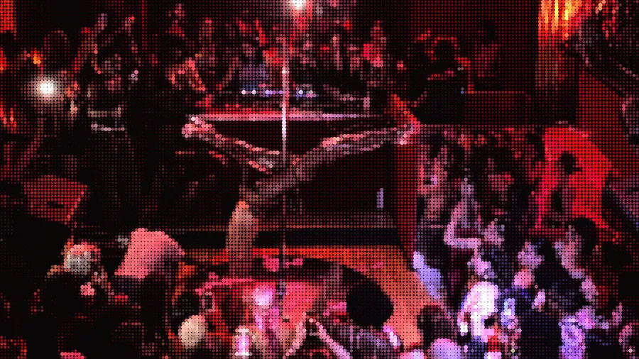 Pole dancer upside down above a red-lit packed crowd