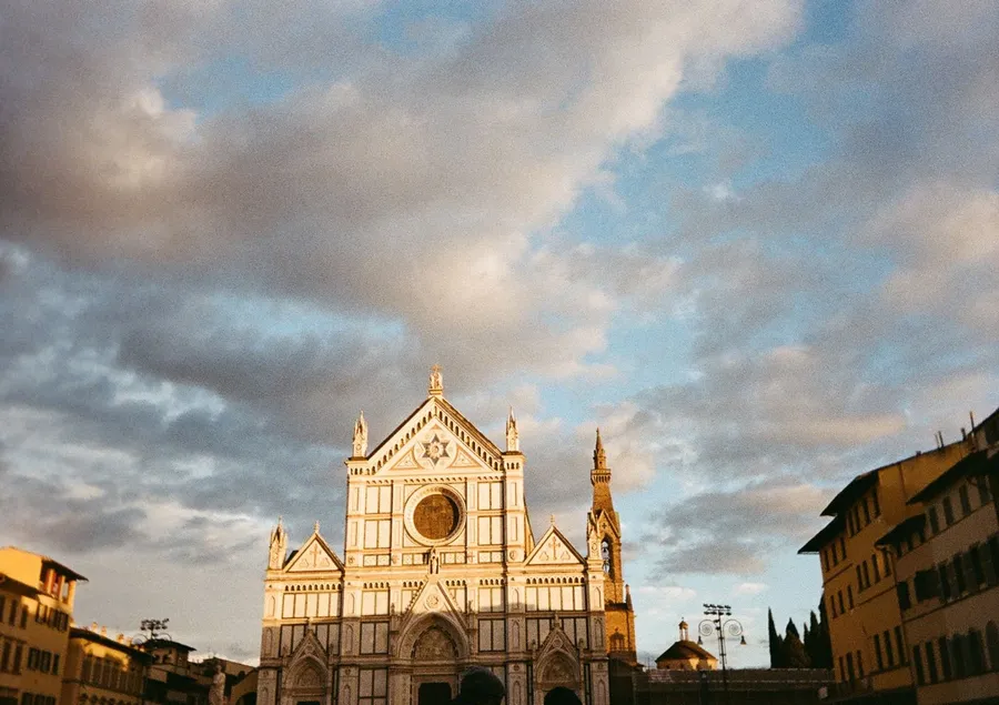 Santa Croce facade glowing gold under streaked clouds