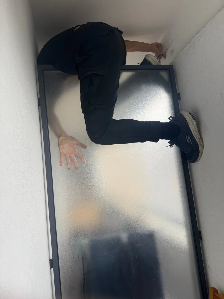 Someone wedged sideways in a narrow gap, legs braced, odd geometry
