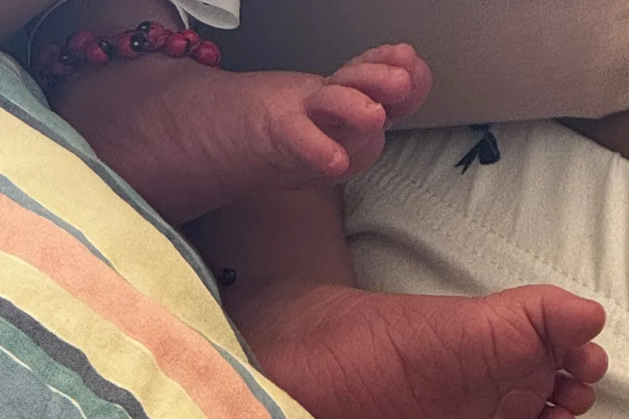 Tiny newborn feet against a striped blanket