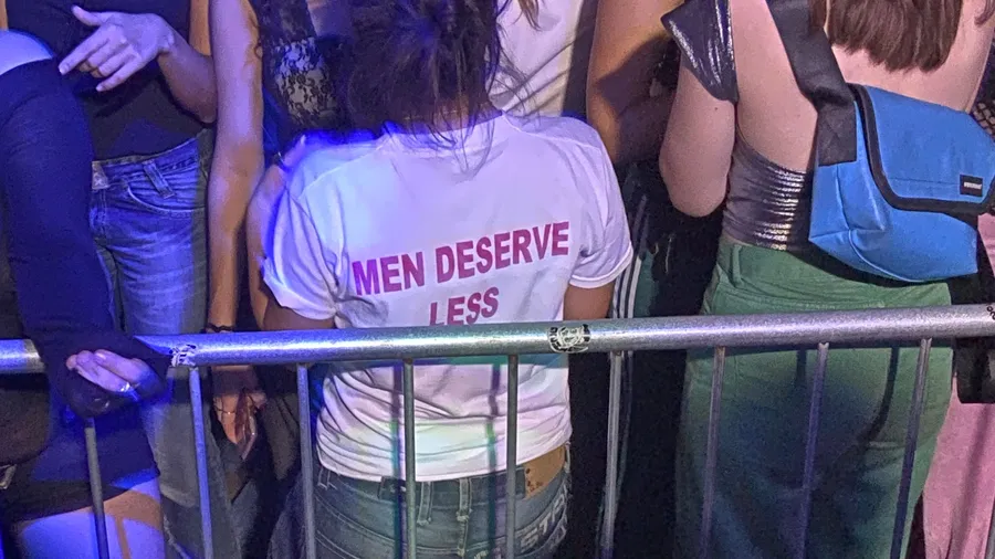 T-shirt slogan 'Men deserve less' in a club crowd at the barrier
