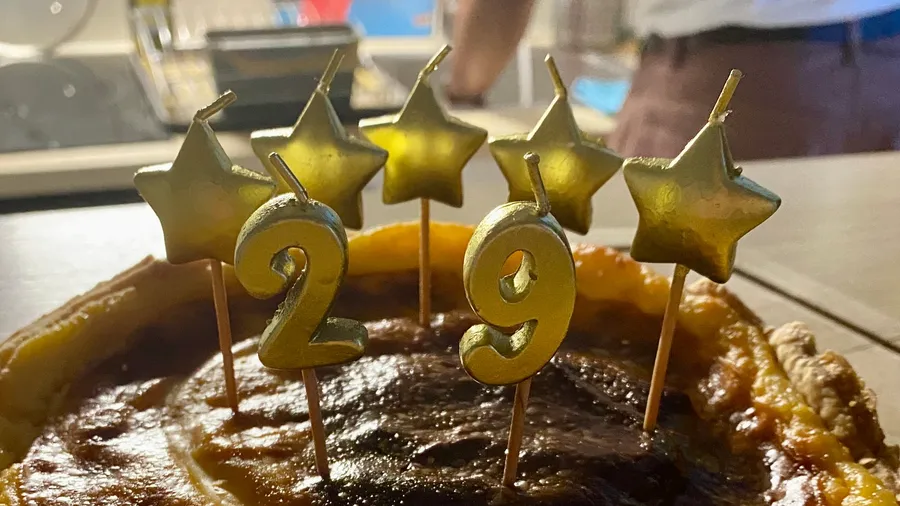 Gold star candles and '29' on a dark birthday cake
