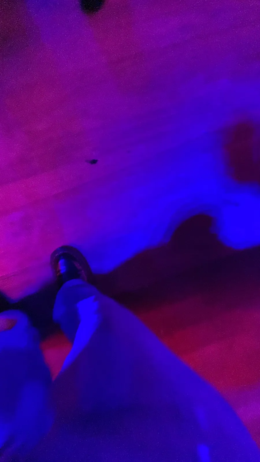 Feet on floor drenched in violet-blue party light