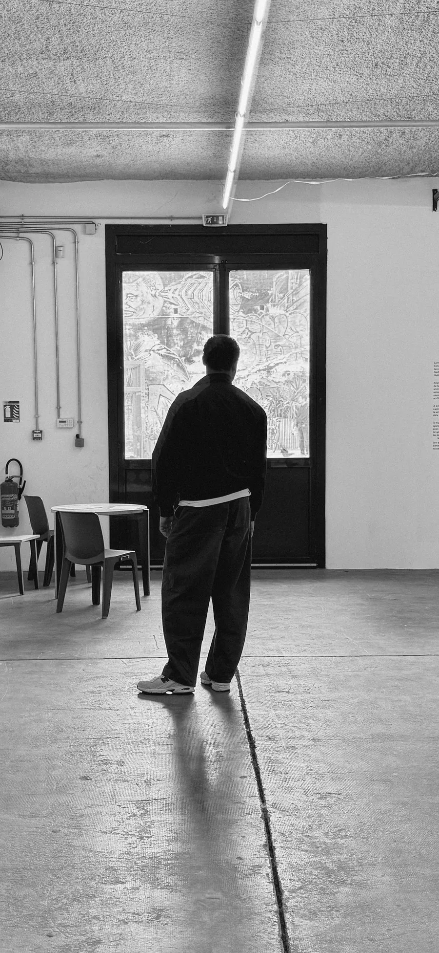 Figure seen from behind facing a bright door in a bare hall