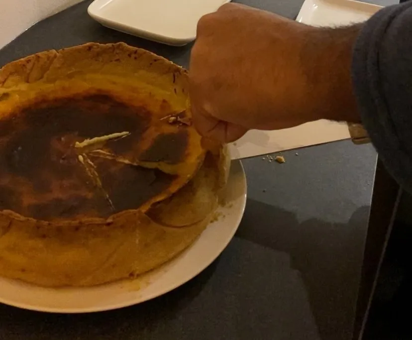 Burnt Basque cheesecake being cut, hand in frame