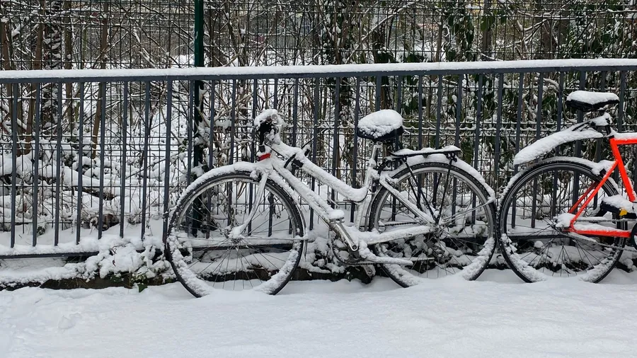 Two bikes buried in snow against a railing