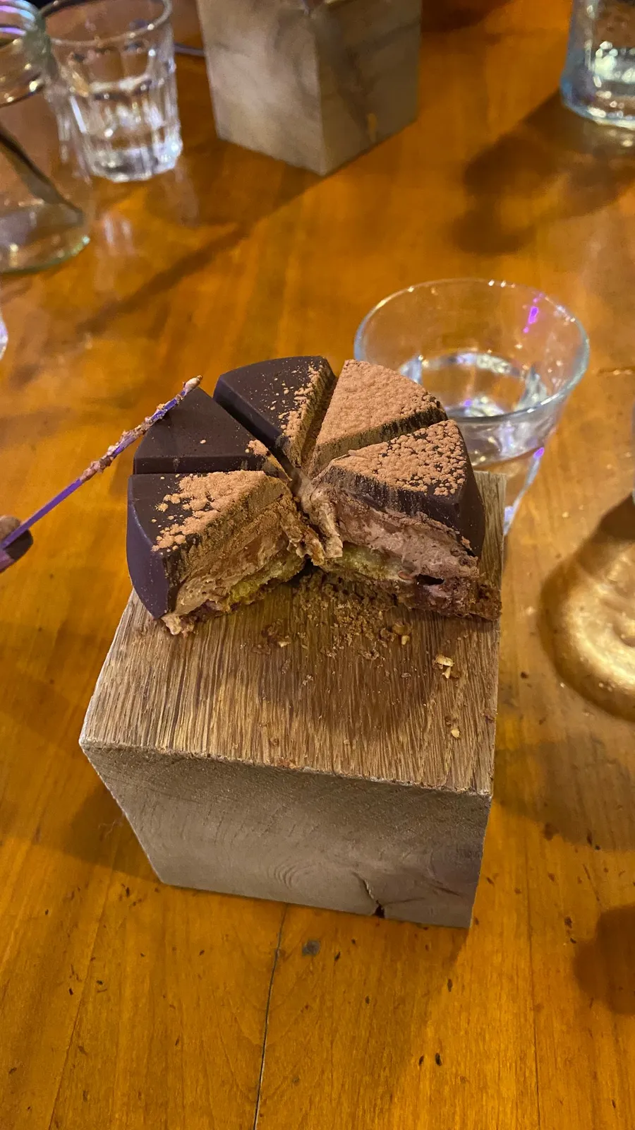 Chocolate cake slice balanced on a wooden block