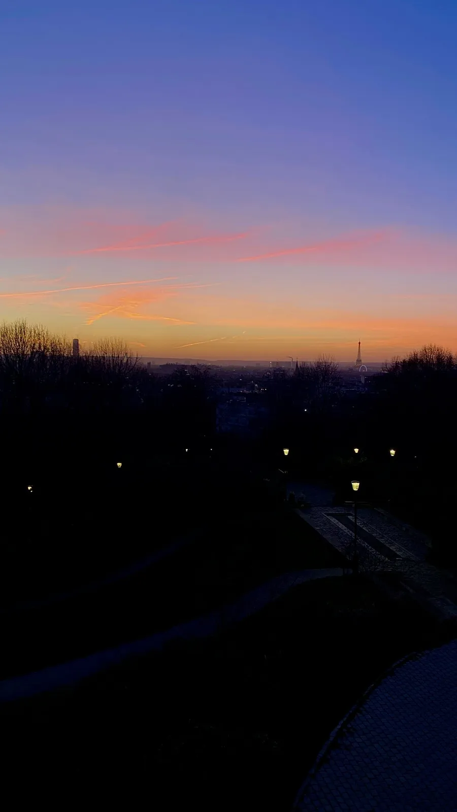 Last pink-orange band of dusk over a dark city, tiny lights