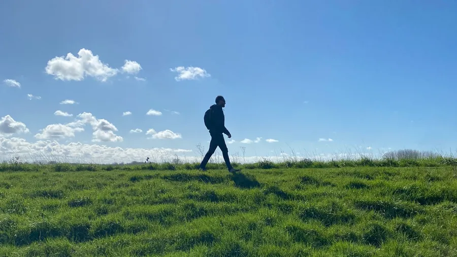 Tiny walking silhouette against huge sky and grass, Bay of Somme