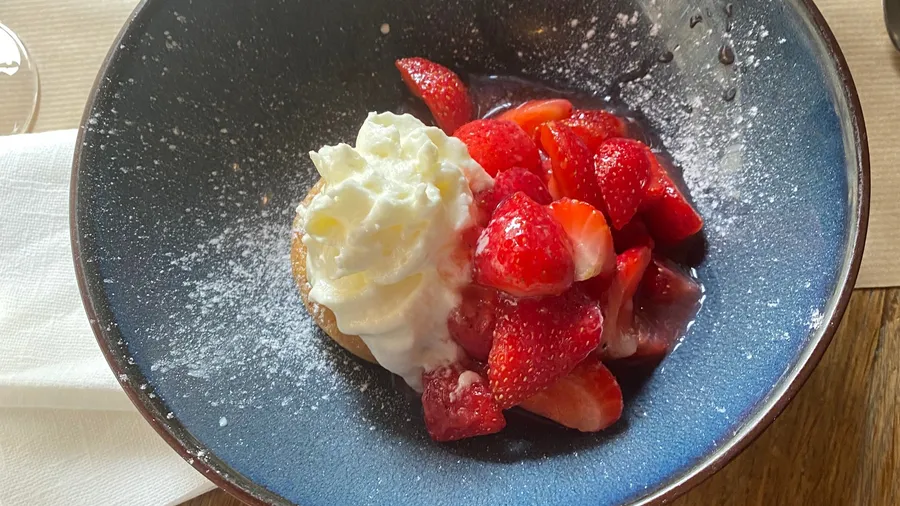 Strawberries with whipped cream and sugar in a blue bowl