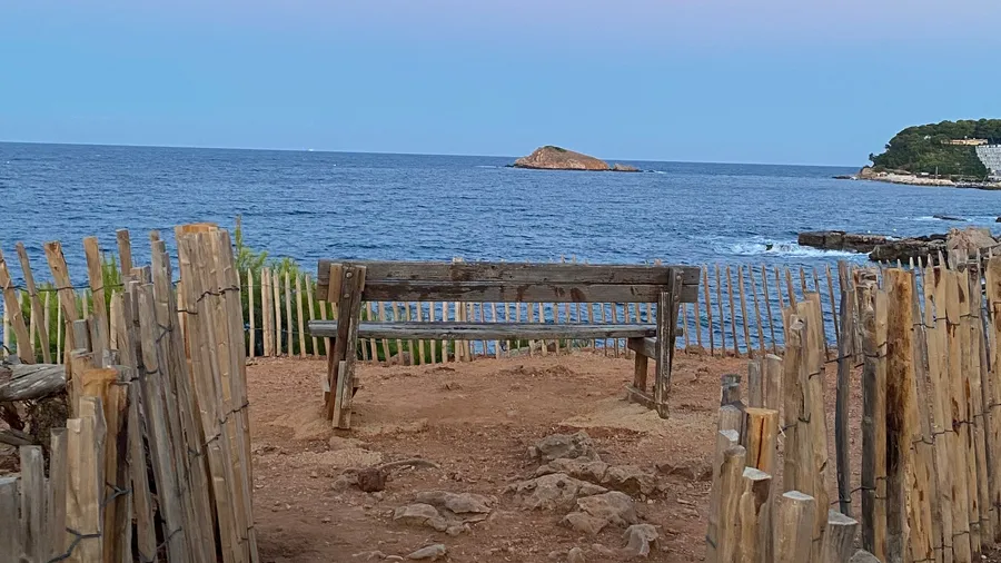 Bench behind wooden fences facing the sea and a small island