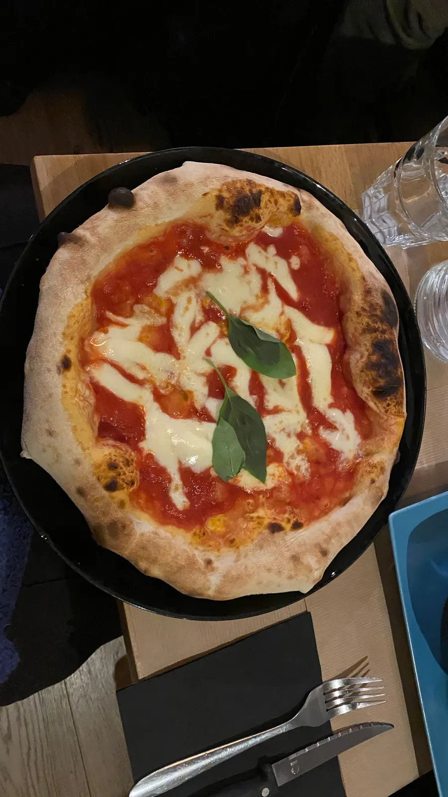 Margherita pizza in a dark pan, seen from above