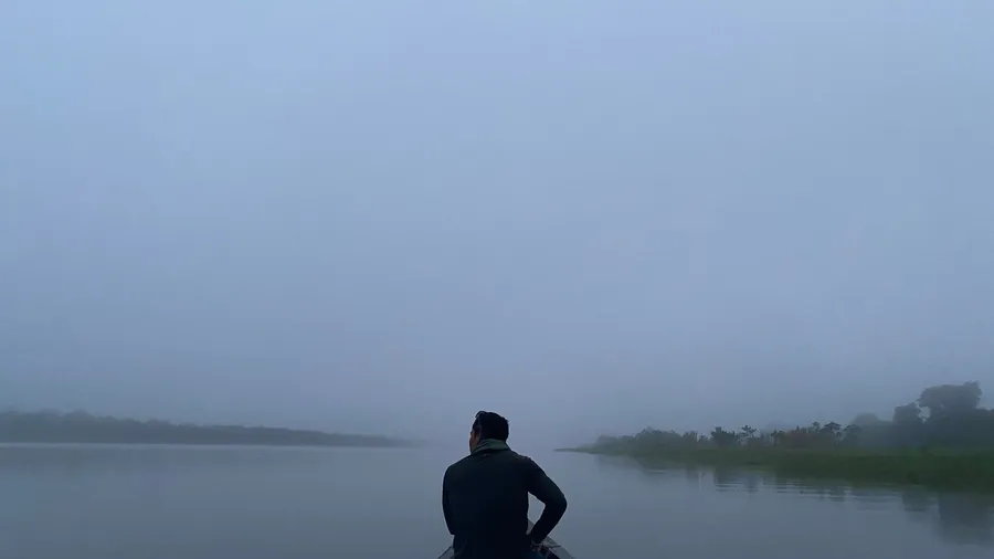 Lone silhouette facing a misty Amazon river at dawn, very still