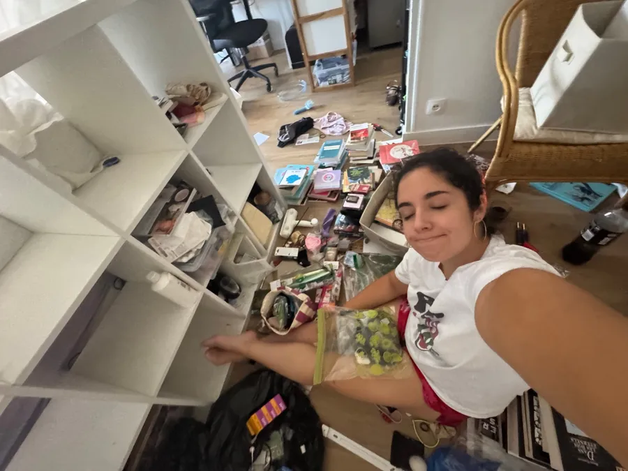 Sitting amid the chaos of an emptied shelf, wry smile