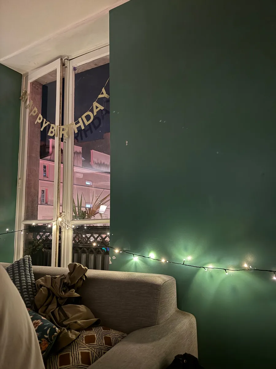 Happy Birthday garland, fairy lights, dark green wall at night