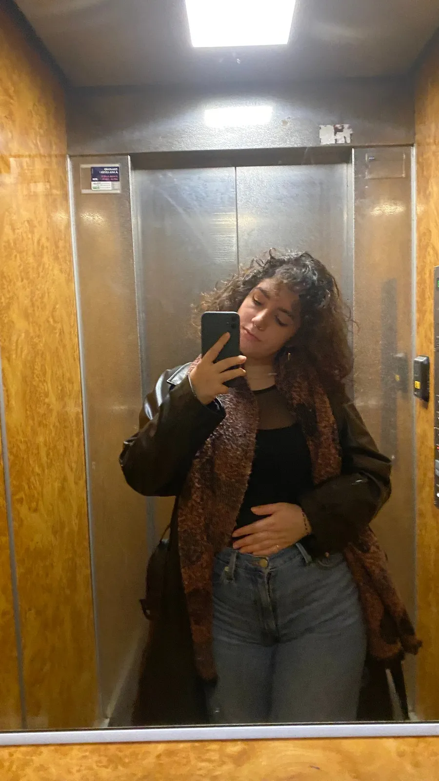 Lift mirror selfie, patterned scarf, warm wood panels