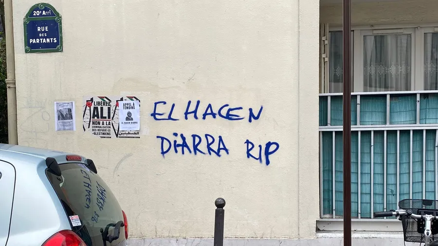 'Elhacen Diarra RIP' in blue on a Paris wall, posters beside