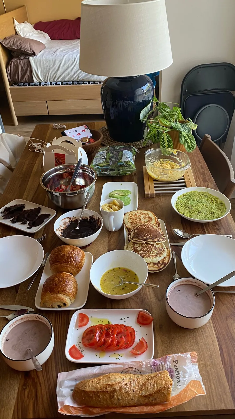 Generous brunch table spread from above, lamp and bed behind