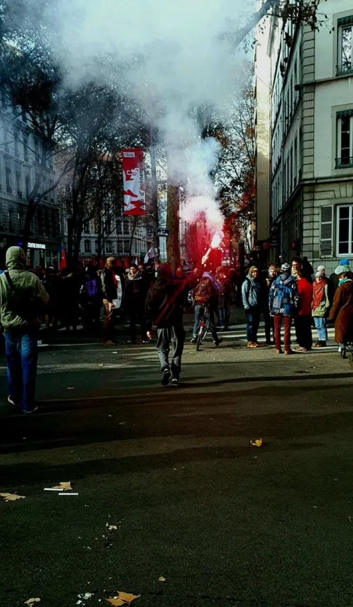 Protest with red flares and smoke between tall buildings
