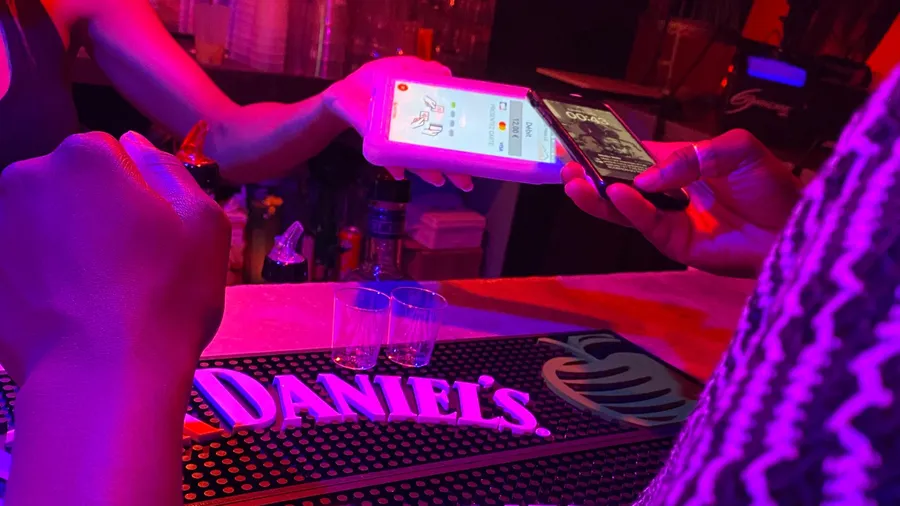 Paying by phone at a neon-pink bar, Daniel's mat, two shot glasses