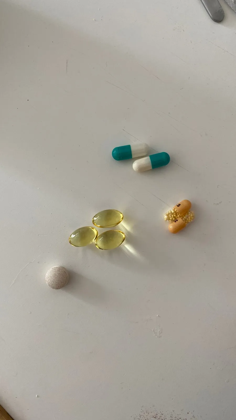Colourful pills and capsules scattered on a white table