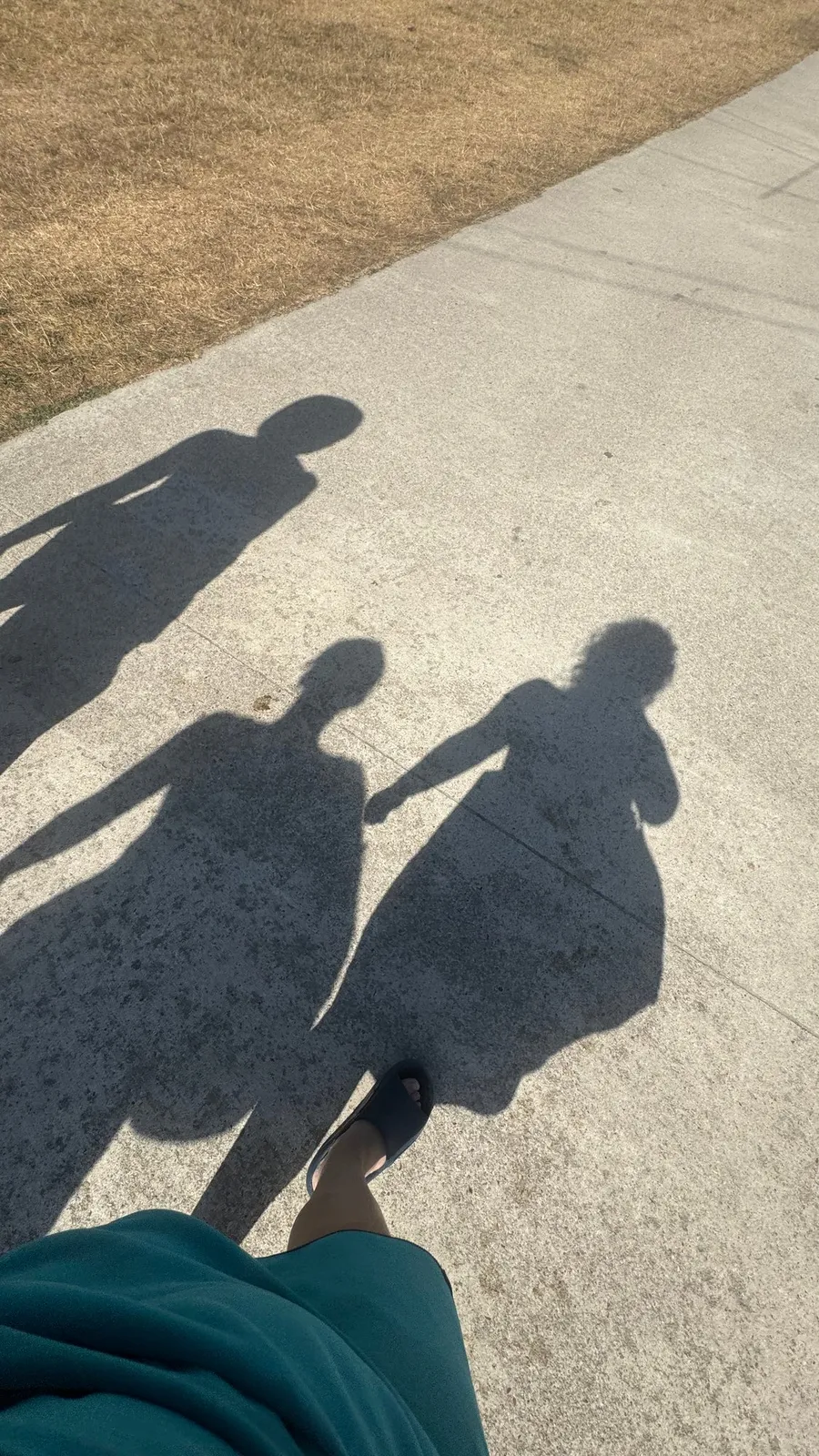 Two long shadows holding hands on a pavement