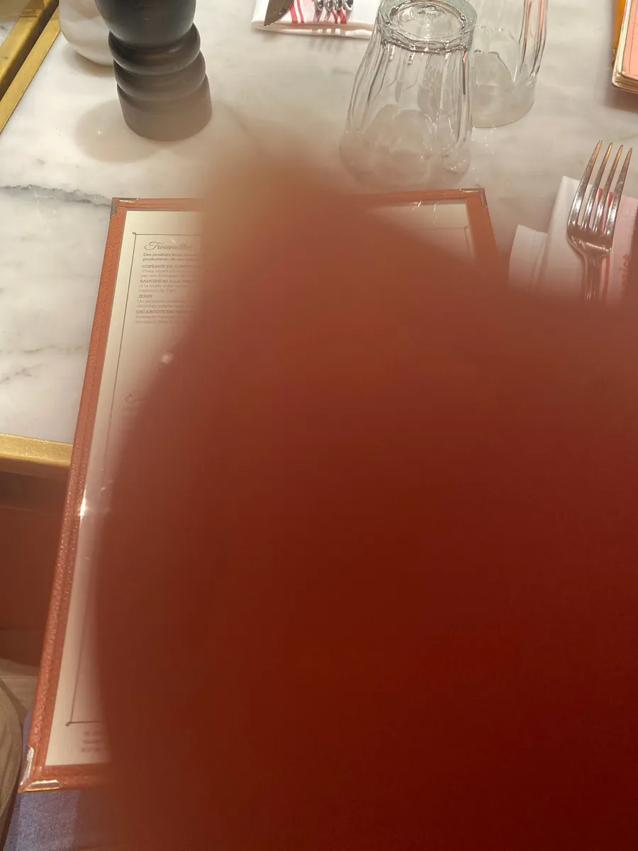 Finger over the lens, a red blur on a café table