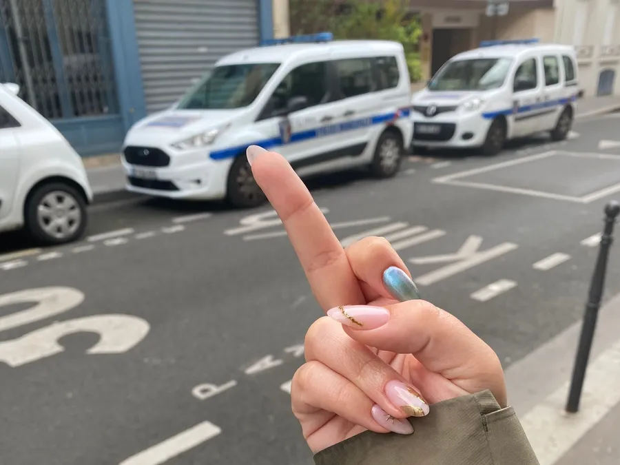 Painted-nail finger pointing at two police cars