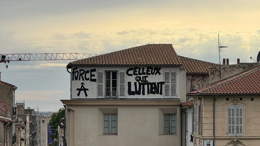 Banner on a roof: 'Force à celles qui luttent'