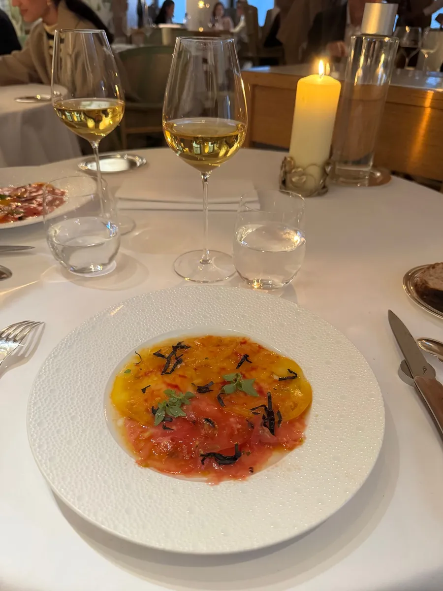 Restaurant course: tomato dish, wine glasses, candle