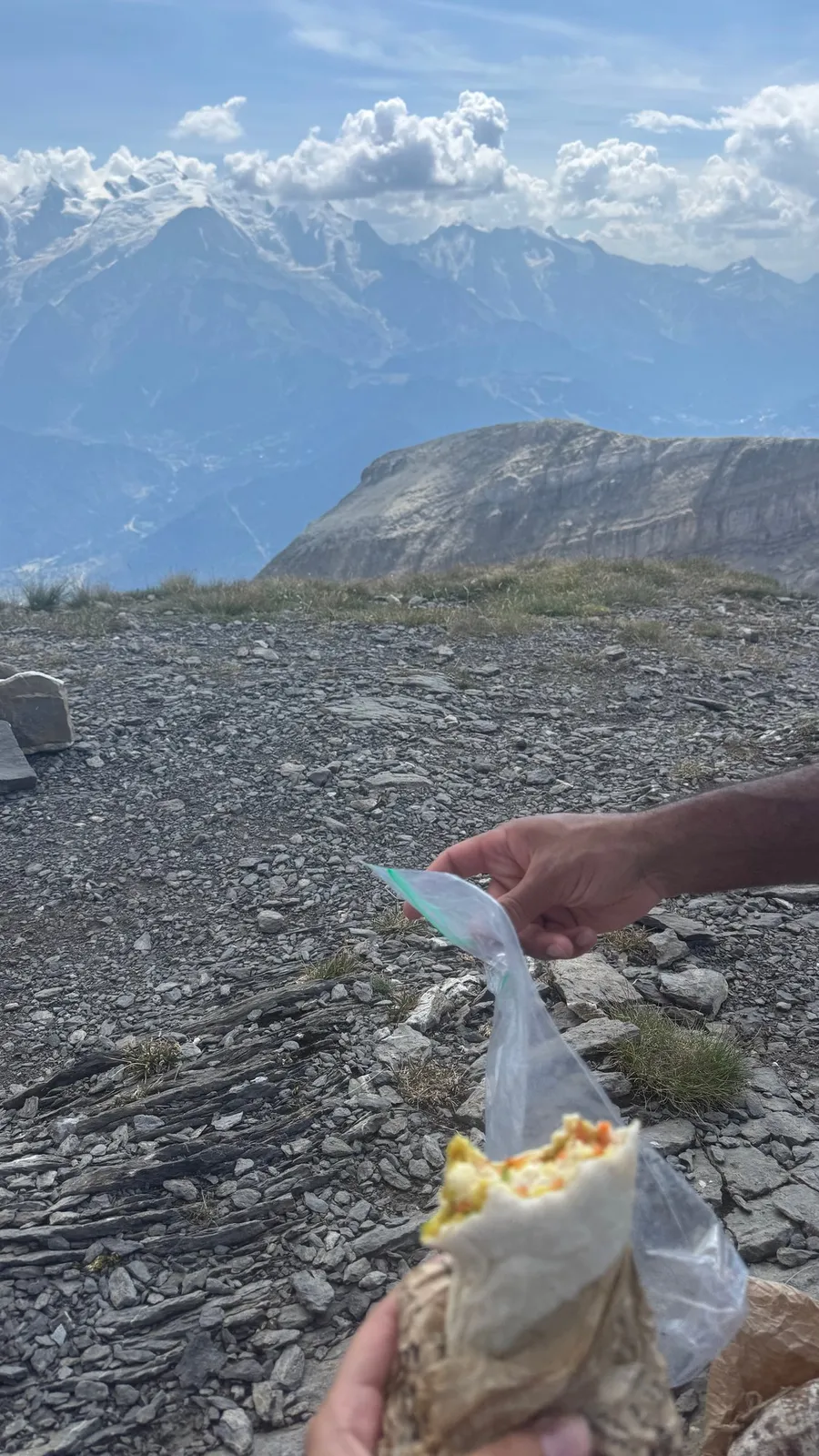 Sandwich in a plastic bag held up on a scree summit