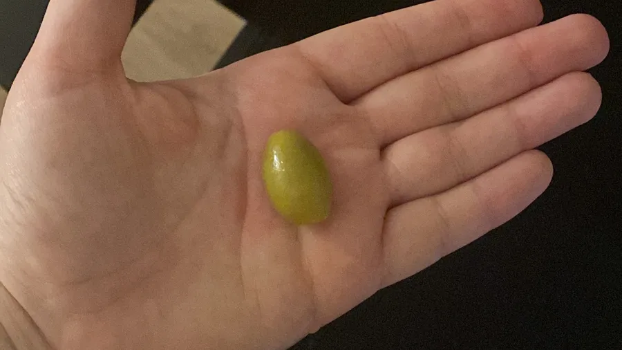 One green olive resting in an open palm