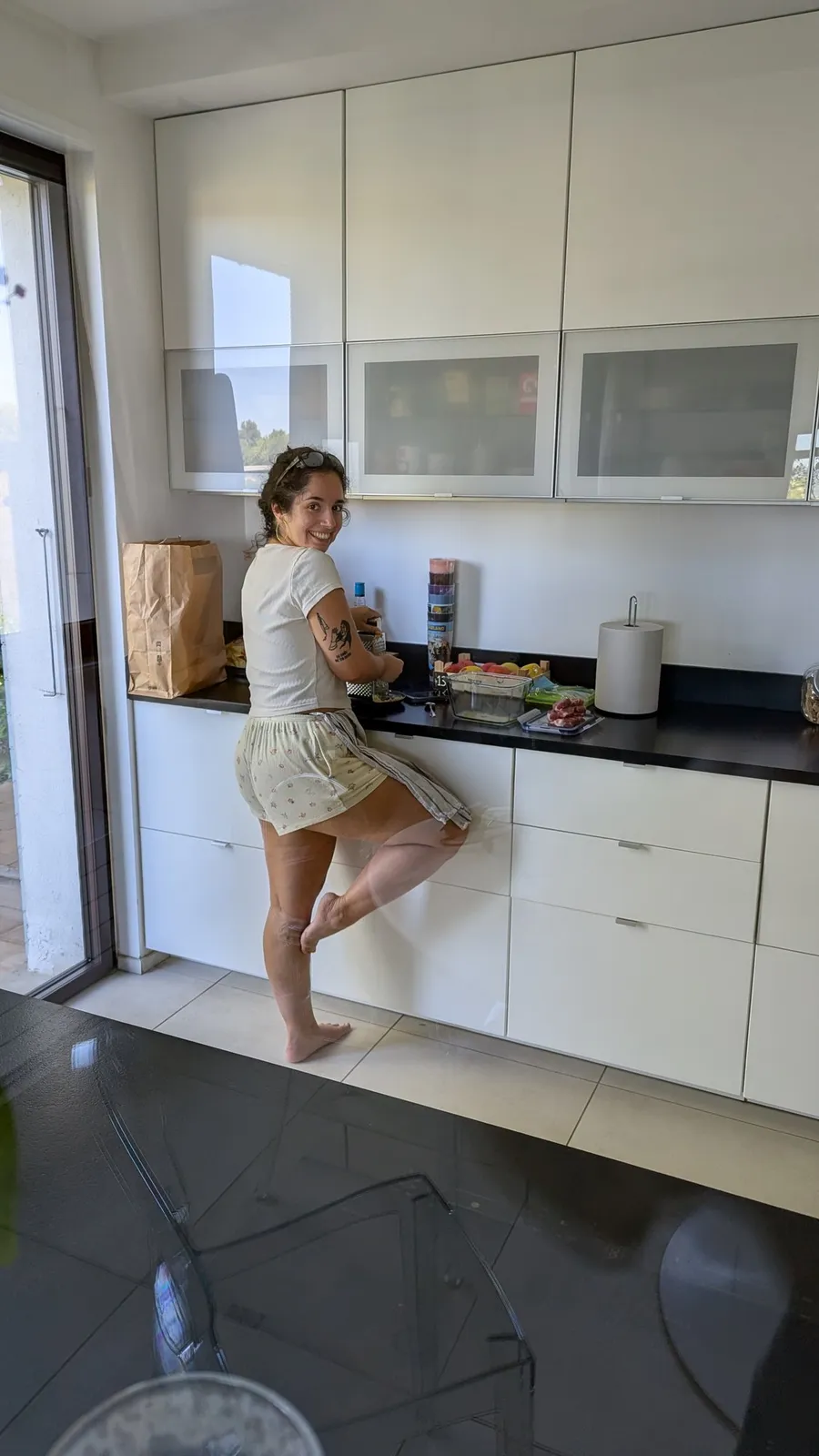 Friend balancing on one leg in a white kitchen, laughing