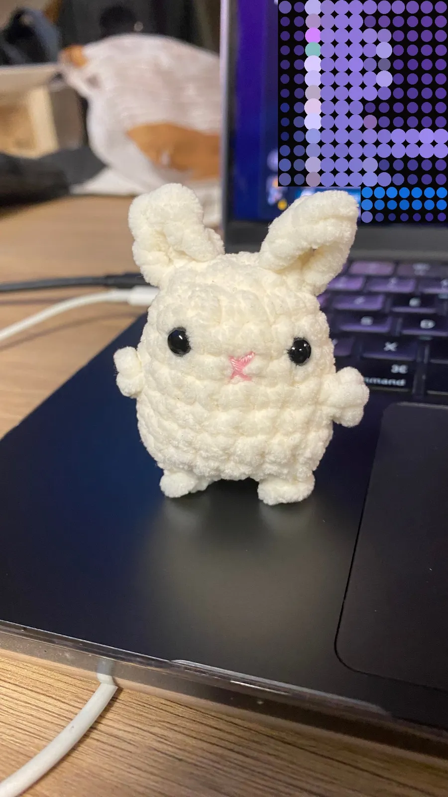 Tiny crocheted bunny standing on a laptop